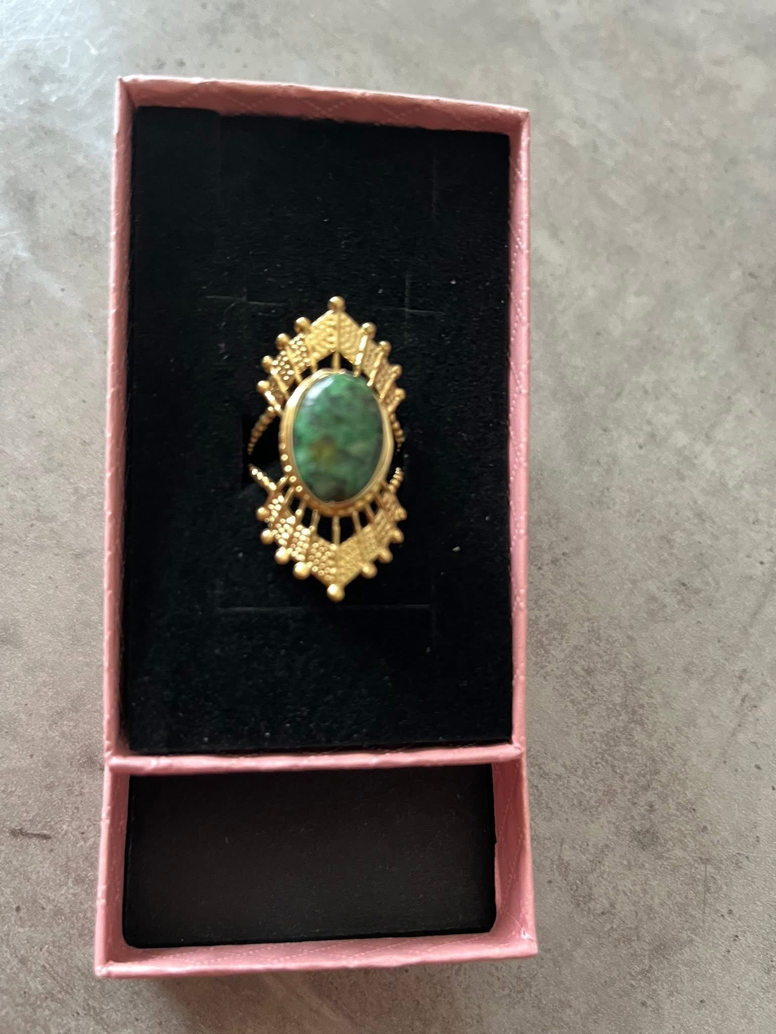 Bague dorée ajustable style solaire avec pierre ovale verte et détails ciselés